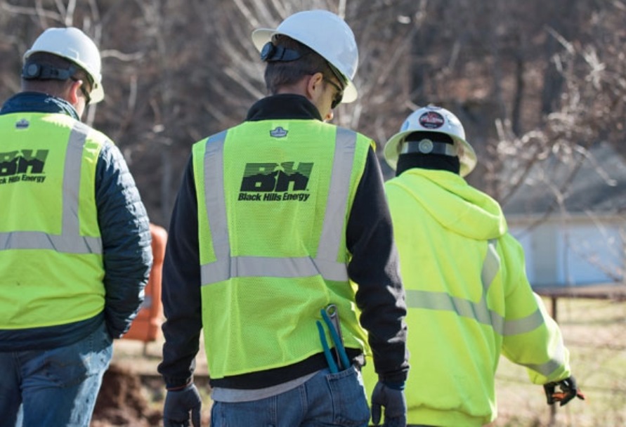 Three people wearing high-vis vests with their backs to the camera