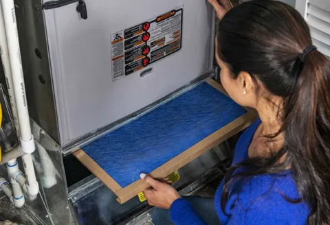 Woman changing furnace filter