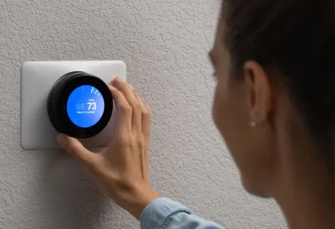 Woman adjusting a smart thermostat