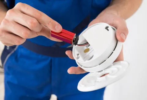 Close up of a person holding a CO detector and it's battery